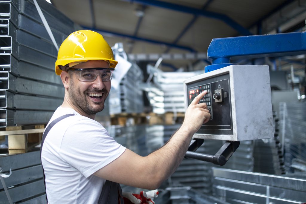 portrait of factory worker operating industrial machine and setting parameters on the computer.
